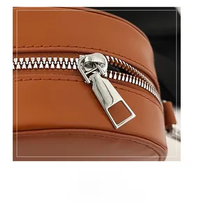 Detail of silver hardware zipper and smooth brown leather texture on shoulder bag