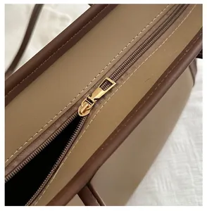 Detailaufnahme des goldenen Reißverschlusses an einer braun-beigen Leder-Tragetasche