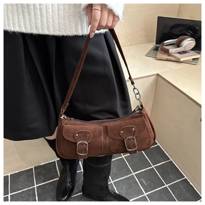 Détail du sac baguette en daim marron avec boucles vintage sur marches en bois