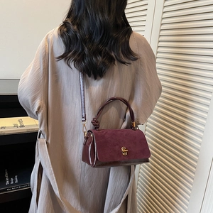 Minimalist burgundy suede handbag with knotted handle and gold twist lock closure