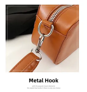 Detail of premium silver metal hook and smooth zipper on a brown leather shoulder bag