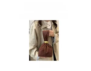 Detail of a brown suede bucket bag featuring a prominent gold metal ring clasp closure