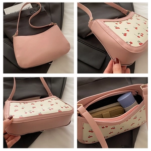 Detail view of pink underarm bag with cherry print, showing interior capacity and stitching