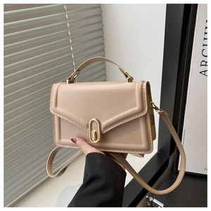 Detail of apricot crossbody bag showing textured flap and gold oval lock mechanism