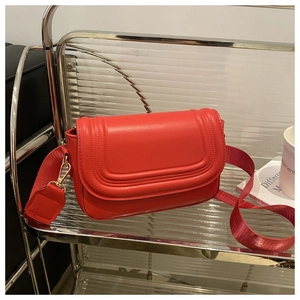 Detail of red saddle bag featuring smooth faux leather and adjustable nylon strap