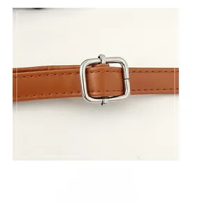 Detail of brown leather shoulder strap with adjustable silver square metal buckle