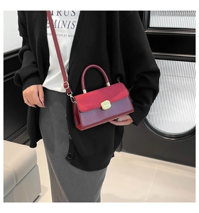 Close-up of a burgundy patent leather handbag with gold clasp and elegant top handle