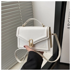 Close-up of white leather square handbag featuring a prominent gold oval twist lock