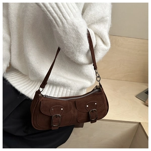 Gros plan d'un sac baguette en daim marron avec boucles argentées vintage et poches