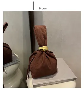 Detail of brown suede bucket bag with elegant large golden metal ring handle on books