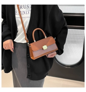 Detail of a brown PU leather crossbody bag featuring a golden clasp and sturdy top handle
