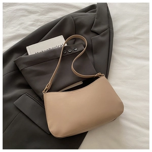 Detail of minimalist beige faux leather shoulder bag on a stylish grey blazer background