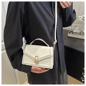 Close-up of a white envelope-style handbag with gold oval clasp and crossbody strap