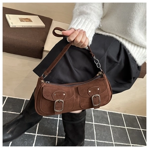 Détail du sac sous le bras en daim marron avec design vintage et boucles en métal argenté