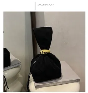 Detail of black suede drawstring bucket bag with a decorative gold oval metal ring