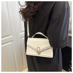 White leather handbag with gold metal lock showing proportional size on model shoulder