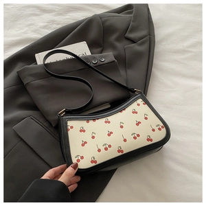 Close-up of cream underarm bag with cherry print on dark grey suit jacket