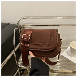 Close-up of vintage dark brown suede saddle bag with fine stitching and gold hardware