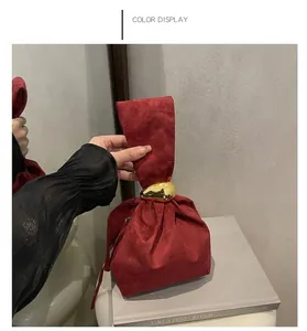 Detail of red suede bucket bag featuring a polished gold metal ring closure