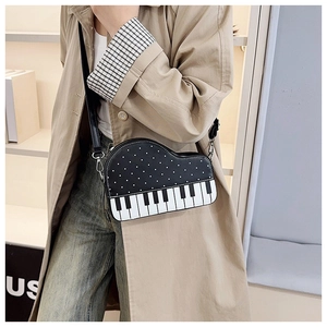 Detail of creative piano-shaped crossbody bag with white dots and piano key pattern
