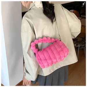 Détail d'un sac à bandoulière en fausse fourrure rose avec poignée tressée et chaîne