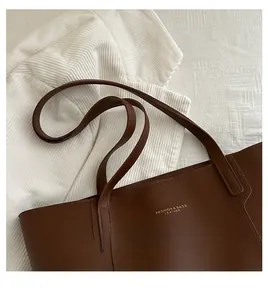 Detail view of deep brown flat-grain leather tote bag with gold lettering and sturdy handles