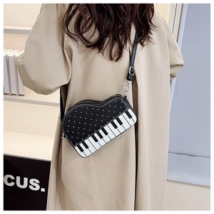 Detail of creative piano-shaped crossbody bag with polka dots on a shoulder model