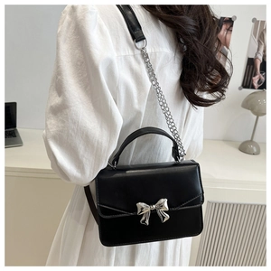 Close-up of black PU leather square bag with silver metal bow clasp and chain strap