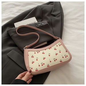 Detailed view of pink and beige cherry print underarm bag with smooth PU leather texture