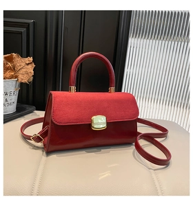 Detail of dark red flap bag with suede texture and elegant gold rectangular clasp