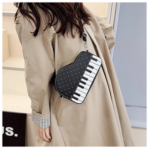Detail view of piano-themed crossbody bag with keyboard pattern and polka dots on model
