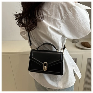 Detail of black crossbody bag with champagne gold metal clasp and premium leather texture