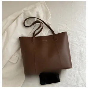 Detail of premium brown leather tote bag with subtle gold logo on minimalist fabric