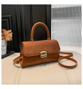 Detail of caramel brown handbag with matte suede flap and gold metal snap buckle