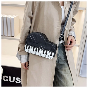 Detail of creative piano-shaped crossbody bag with polka dots and black-white keys print