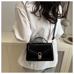 Detail of black square handbag showing elegant gold clasp and vegan leather texture