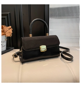Detail of black crossbody bag with mixed leather textures and gold square metal buckle