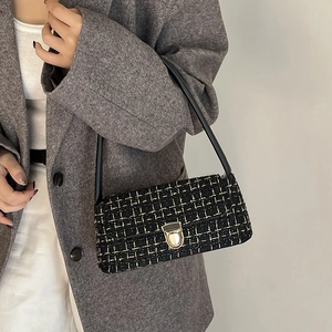 Elegant black tweed shoulder bag with gold metal buckle and leather strap on model