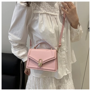 Detailed close-up of a pink faux leather handbag featuring a golden metallic twist-lock