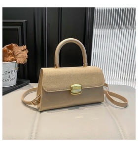 Detail of beige flap bag with textured suede finish and gold square metal buckle clasp