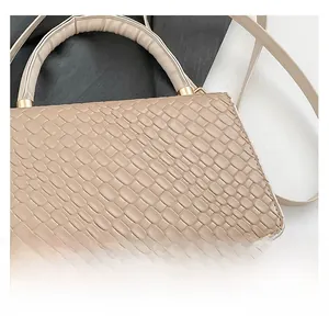 Close-up of beige crocodile embossed leather handbag with golden metal hardware and round handle