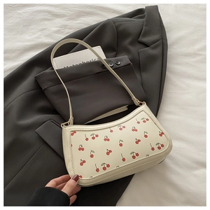 Close-up of French vintage underarm bag with red cherry print on cream PU leather