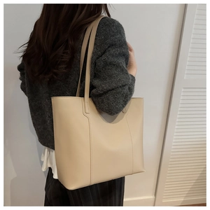 Side view of a large beige tote bag worn by a model for daily commuting style