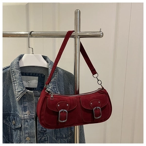 Détail du sac sous l'aisselle en daim bordeaux vintage avec boucles et poches frontales