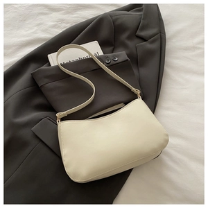 Close-up of cream PU leather underarm bag placed on a grey blazer with minimalist chain