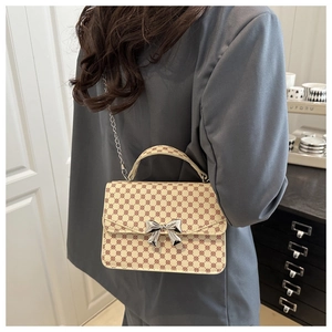 Detail of vintage patterned crossbody bag with silver bow buckle on grey blazer