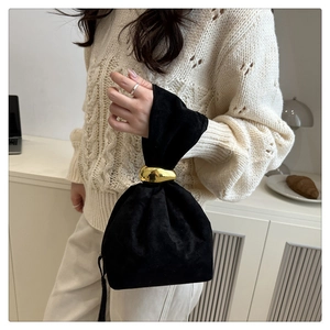 Detail of velvet drawstring bag featuring a sleek golden metal ring handle for elegant style