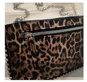 Detail showing smooth silver metal zipper and rivet accents on leopard print crossbody bag