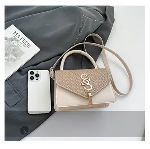 Detail of beige flap bag with woven texture, golden S-buckle, and smartphone for scale
