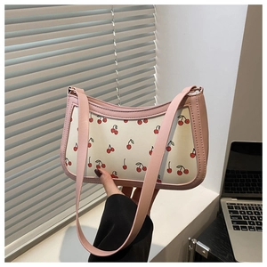 Detail of pink leather trim and vibrant cherry pattern on a white shoulder bag